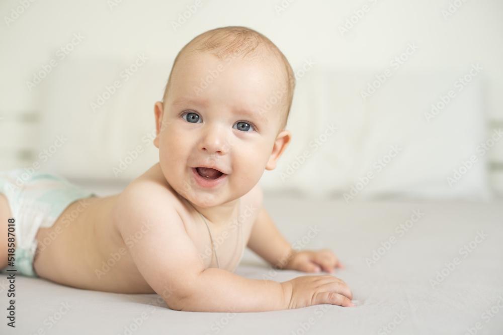 Adorable baby boy in white sunny bedroom. Newborn child relaxing in bed. Nursery for young children. Family morning at home. New born kid Adorable baby boy in white sunny bedroom. Newborn child relaxing in bed. Nursery for young children. Family morning at home. New born kid