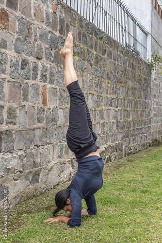 Young woman headstand in yoga salamba sirsasana position outdoors photo