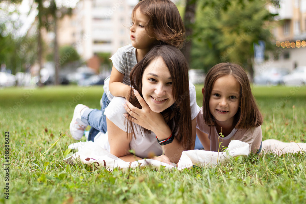 Happy smiling young woman wear white clothes have fun picnic lying on plaid grass with child baby girl 5-6 years old. Mommy play resting with little kid daughter outdoor together. Love family concept. Happy smiling young woman wear white clothes have fun picnic lying on plaid grass with child baby girl 5-6 years old. Mommy play resting with little kid daughter outdoor together. Love family concept.