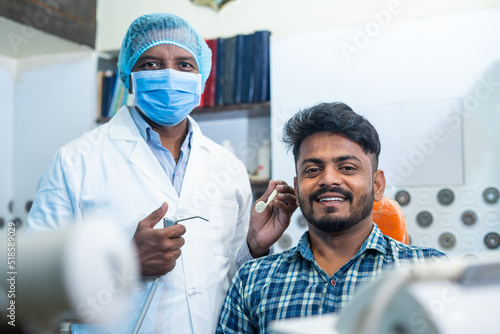 Portrait shot of happy smiling patient with dental doctor or dentist with medical face mask at hosptial looking at camera - concept of oral care, diagnosis and treatment photo