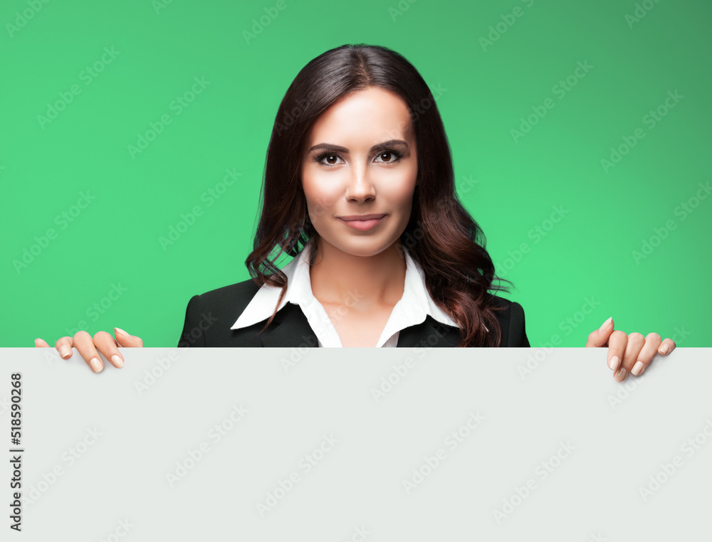 Portrait image of happy smiling young business woman in black suit, showing white signboard with blank copy space area for text, isolated on green background. Portrait image of happy smiling young business woman in black suit, showing white signboard with blank copy space area for text, isolated on green background.