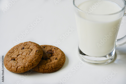 Glass glass with milk on a white background with oatmeal cookies. Afternoon lunch with cookies. Sweet cookies with milk.