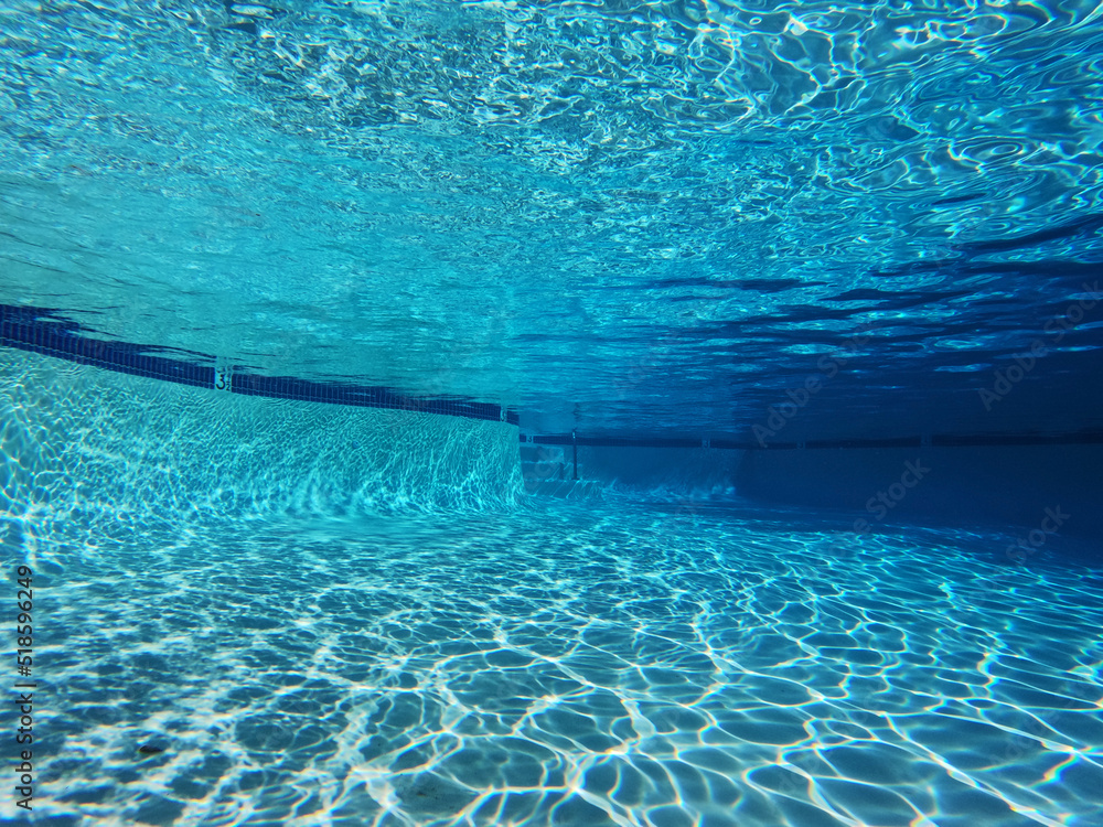 Underwater view of sunlight pattern in large clean swimming pool.