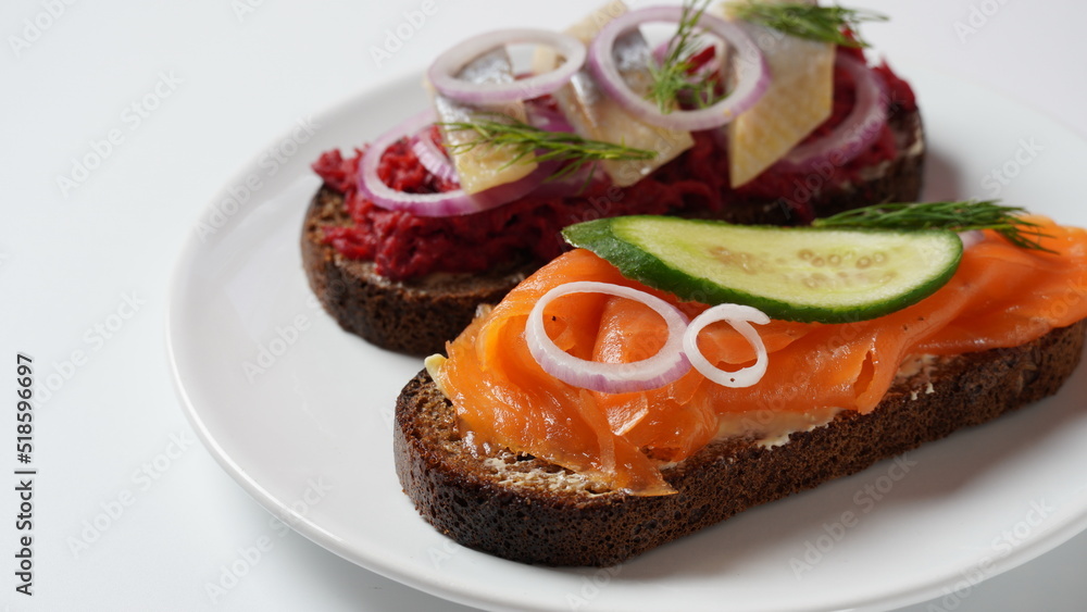 Danish open sandwich Smorrebrod on dark rye bread with herring, salmon, beetroot, red onions, and radish Danish open sandwich Smorrebrod on dark rye bread with herring, salmon, beetroot, red onions, and radish