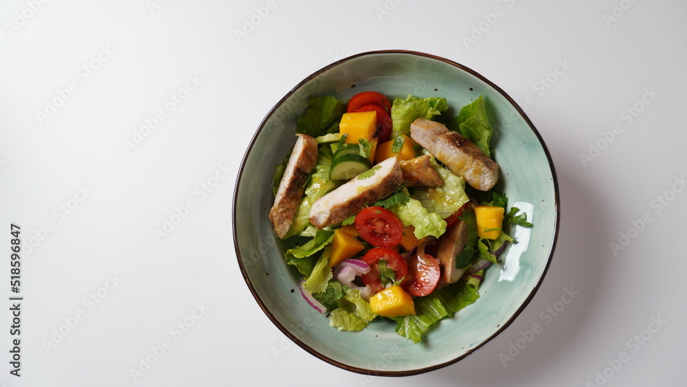 Salad with chicken breast, fresh mango, avocado, cucumber, cherry tomatoes, lettuce. Healthy food concept