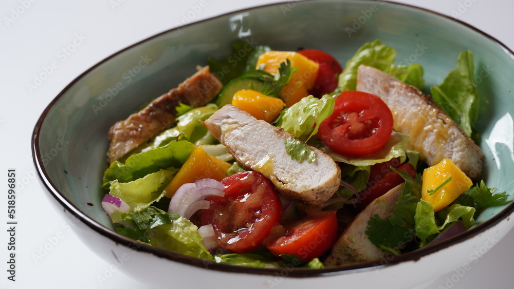 Salad with chicken breast, fresh mango, avocado, cucumber, cherry tomatoes, lettuce. Healthy food concept