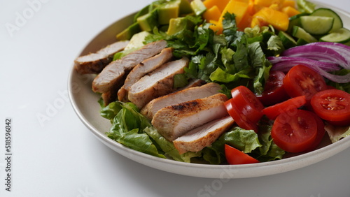 Salad with chicken breast, fresh mango, avocado, cucumber, cherry tomatoes, lettuce. Healthy food concept