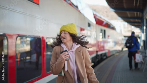 Happy young traveler woman with luggage running to catch the train at train station platform