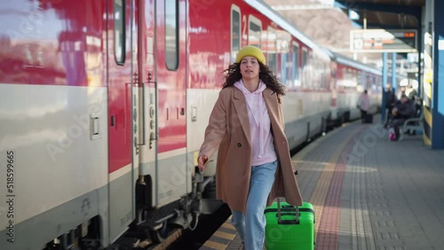 Happy young traveler woman with luggage boarding in the train at train station platform