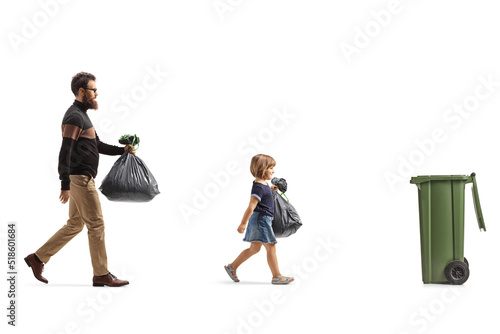 Father and daughter with plastic bags walking towards a trush bin photo