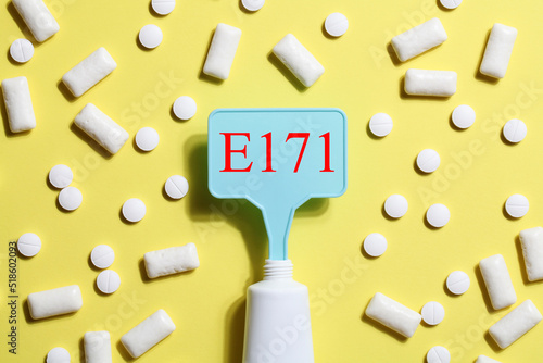 Titanium dioxide, E171, dangerous additive concept. gum, pills, toothpaste or cream and sign with E171 on yellow background. copy space photo