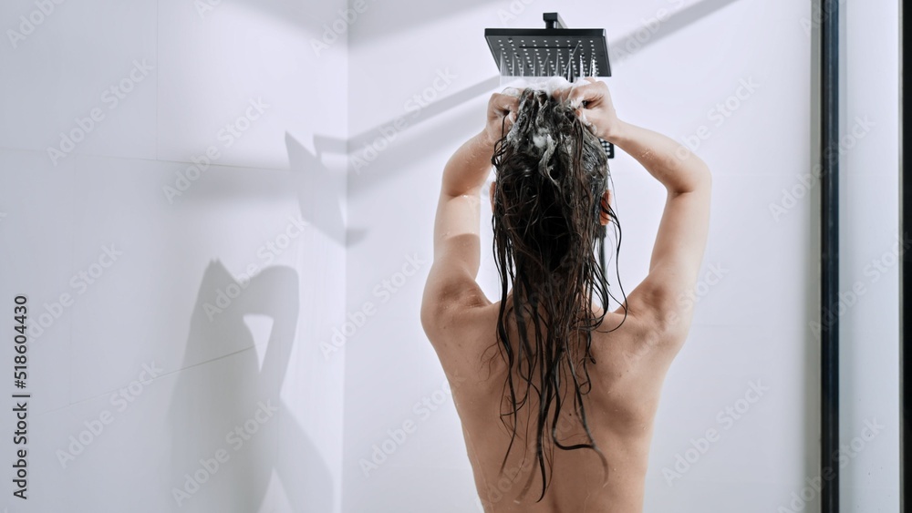 Back shot of a Caucasian female woman taking shower at home - obrazy, fototapety, plakaty 