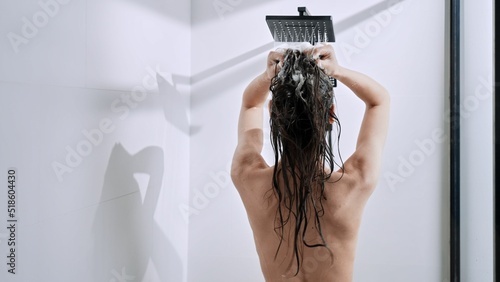 Back shot of a Caucasian female woman taking shower at home