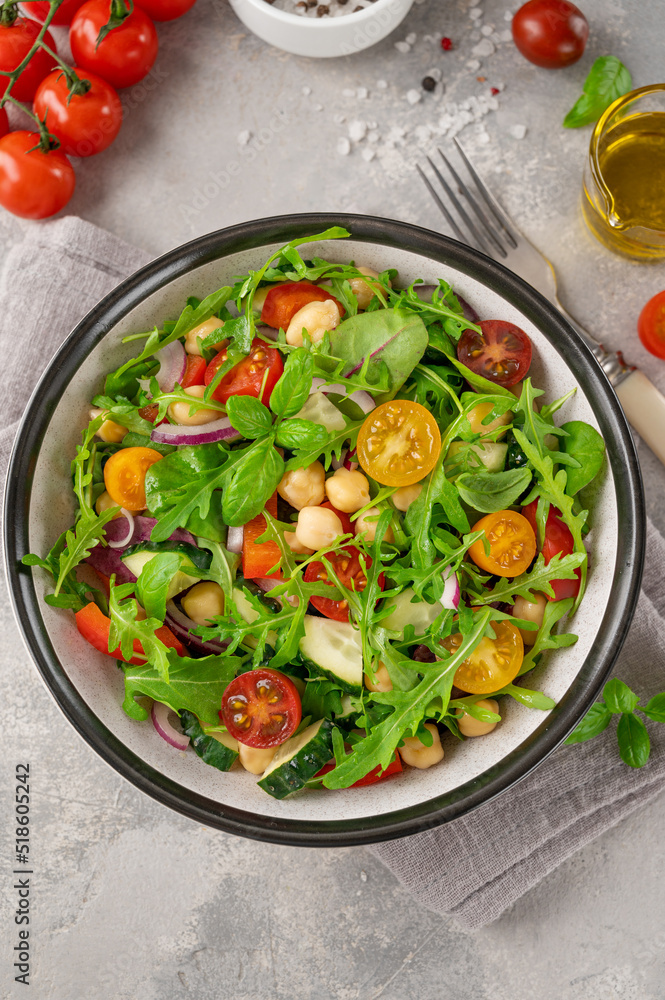 Salad with chickpeas, green leaves and fresh vegetables in a bowl on a gray concrete background. Healthy food. Top view, copy space. Salad with chickpeas, green leaves and fresh vegetables in a bowl on a gray concrete background. Healthy food. Top view, copy space.