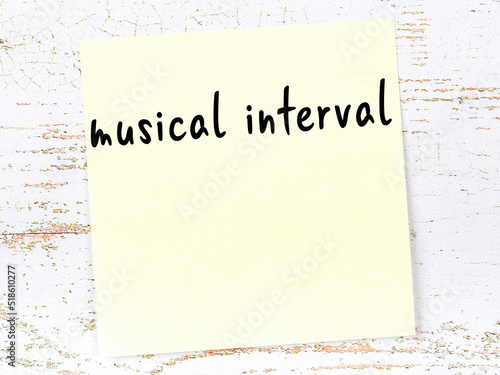 Fotografie Yellow sticky note on wooden wall with handwritten word musical interval