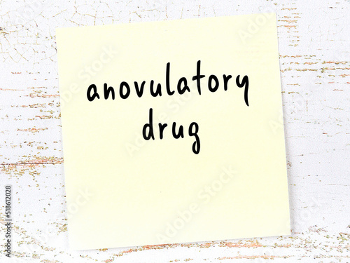 Yellow sticky note on wooden wall with handwritten word anovulatory drug photo