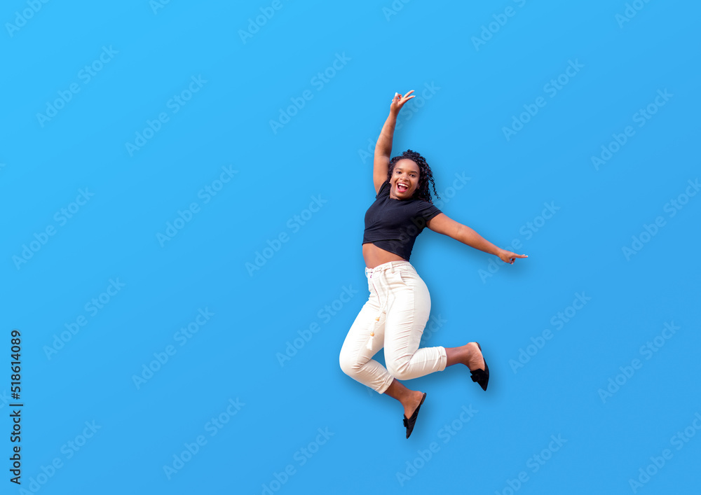 Happy black woman jumping over isolated blue wall
