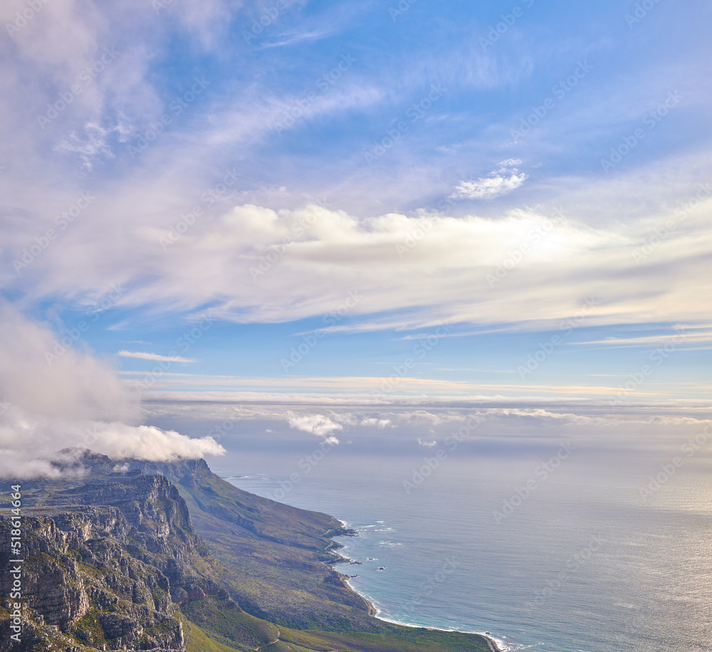 Panorama of a calm ocean and mountains with a cloudy blue cloudy sky background and copy space. Stunning nature landscape of the sea and horizon against The twelve apostles landmark in Cape Town