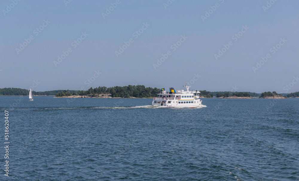 Commuter boat crossing an open bay in the archipelago, islands and sail boat passing a sunny summer day in Stockholm