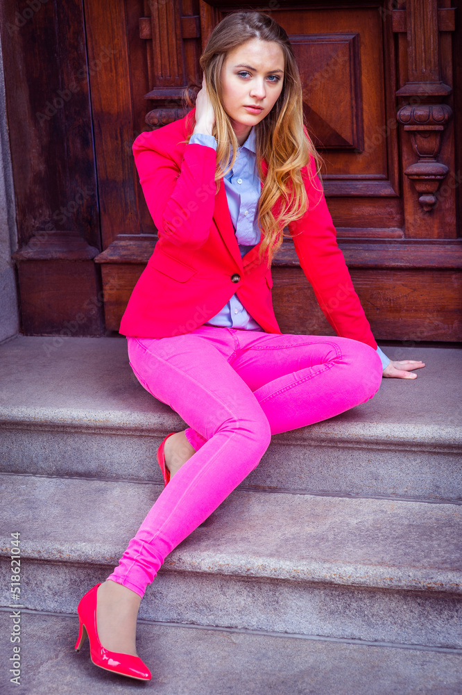 Girl Dressing in Pink. Young teenage girl wearing pink blazer, pink pants, pink shoes, sitting on stairs by office door.