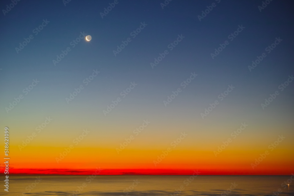 Peaceful ocean landscape at sunset over a calm empty sea at dawn. Wallpaper of stunning red and yellow light reflecting on the water from the midnight sun at twilight dusk with copy space background Peaceful ocean landscape at sunset over a calm empty sea at dawn. Wallpaper of stunning red and yellow light reflecting on the water from the midnight sun at twilight dusk with copy space background
