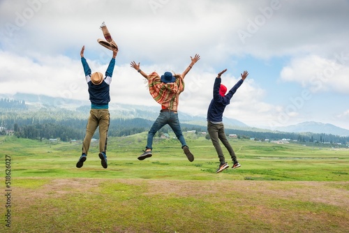 Three young man jumping on meadow photo