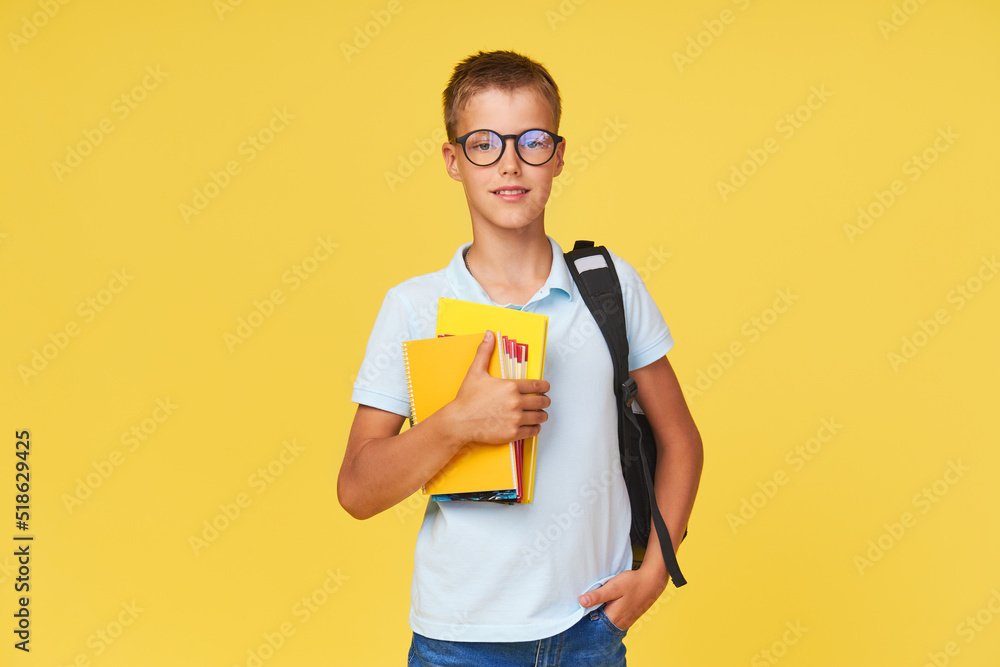 Portrait of a schoolboy in glasses with textbooks and a backpack on a yellow background. Back to school Portrait of a schoolboy in glasses with textbooks and a backpack on a yellow background. Back to school