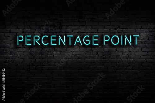 Neon sign. Word percentage point against brick wall. Night view photo