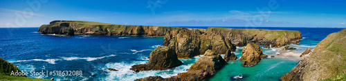 A panorams of the rugged coastal cliff scenery and pristine turquoise waters around the island of Uyea in Northmavine, Shetland, UK. Taken on a sunny day with a blue sky.