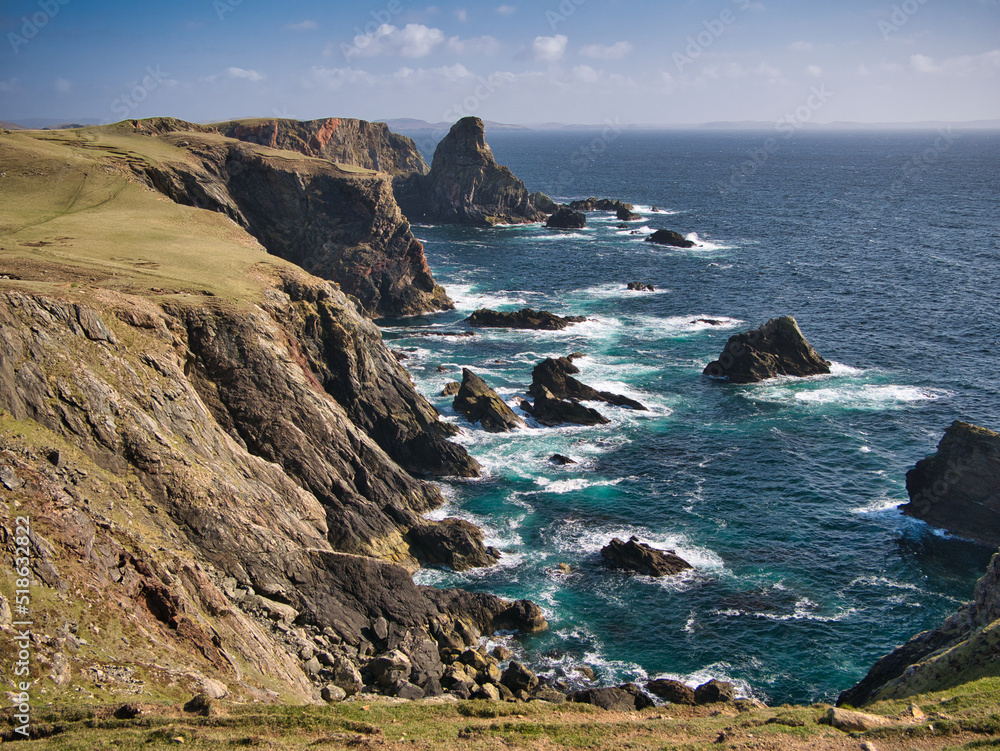 Dramatic coastal cliff scenery on the Ness of Hillswick, Northmavine, in the UNESCO Global Geopark of Shetland, UK - taken on a sunny day showing the clear, blue water of the Islands in the North Sea.