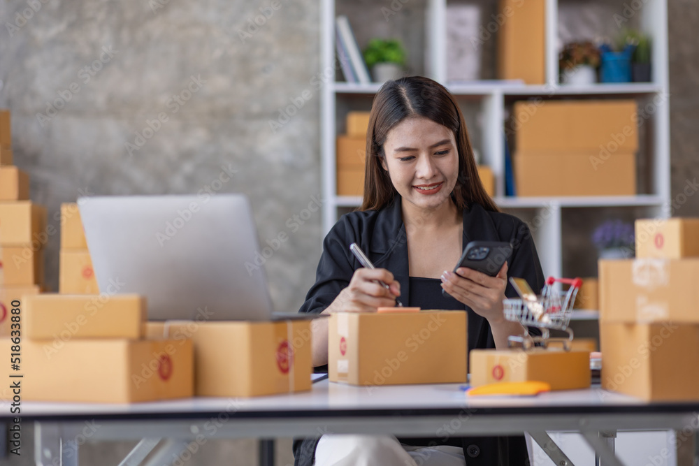Portrait of young Asian woman SME working with a box at home the workplace.start-up small business owner, small business entrepreneur SME or freelance business online and delivery concept. Portrait of young Asian woman SME working with a box at home the workplace.start-up small business owner, small business entrepreneur SME or freelance business online and delivery concept.