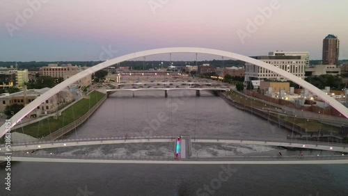 Aerial drone flyover view of Center Street Bridge over Des Moines River in downtown Des Moines, Iowa at sunset in summer.