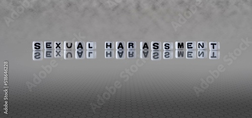 sexual harassment word or concept represented by black and white letter cubes on a grey horizon background stretching to infinity