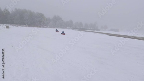 Two kids racing with sleds and one of them ends up capsizing