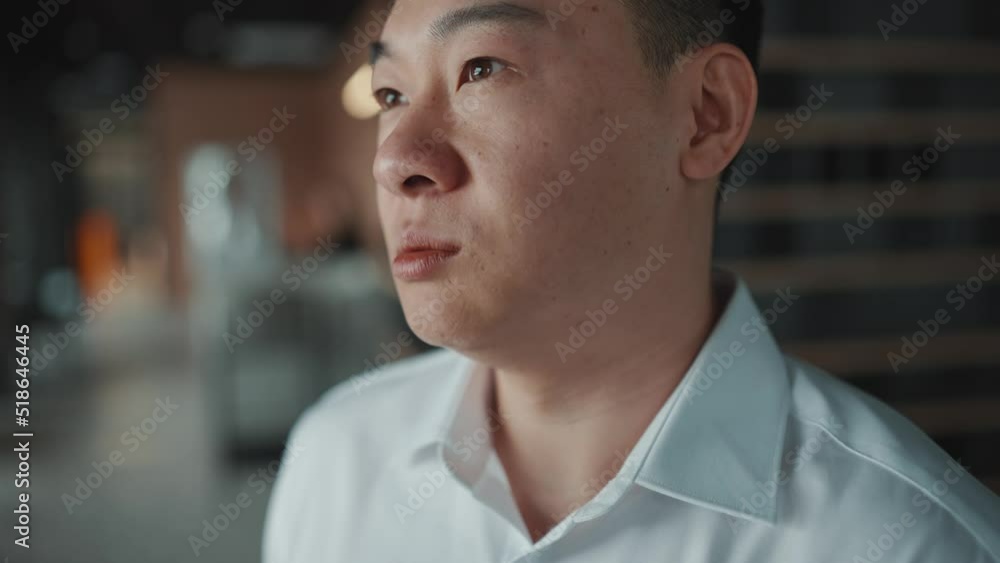 Meditative Asian brunet businessman talking something while standing in the office Meditative Asian brunet businessman talking something while standing in the office