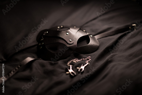 On a black background, a mask and nipple clamps. Role-playing games. BDSM. soft focus