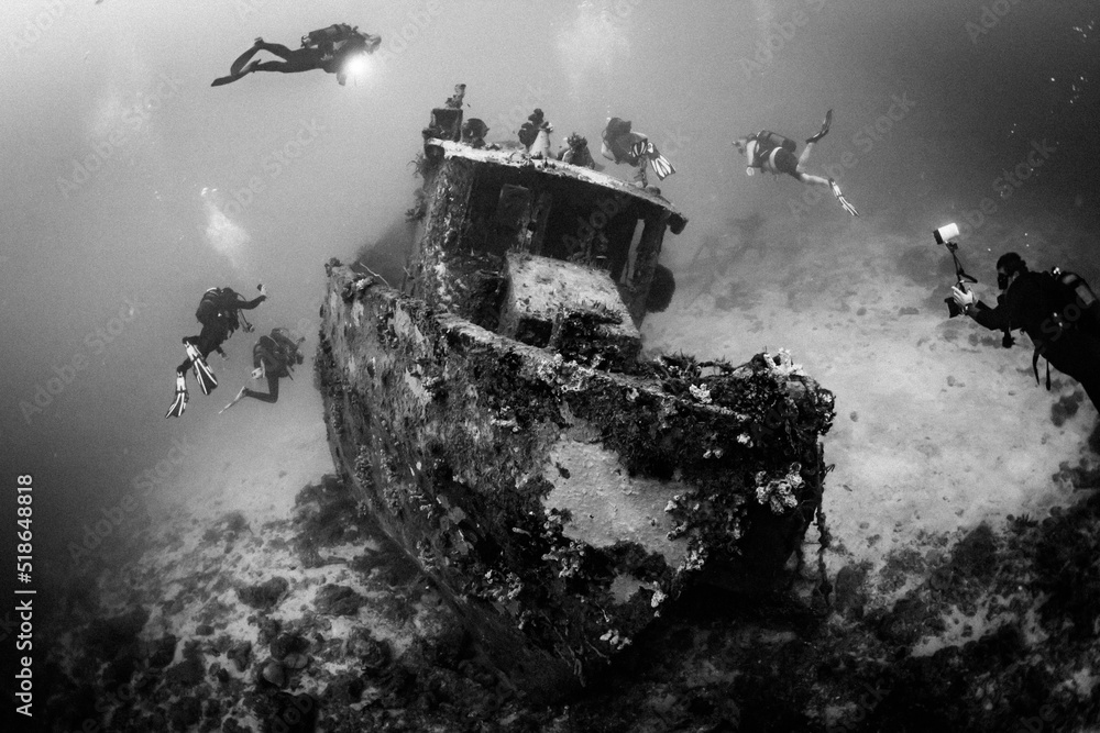 Group of divers exploring sunken ship. Wreck diving on Madagascar - obrazy, fototapety, plakaty 