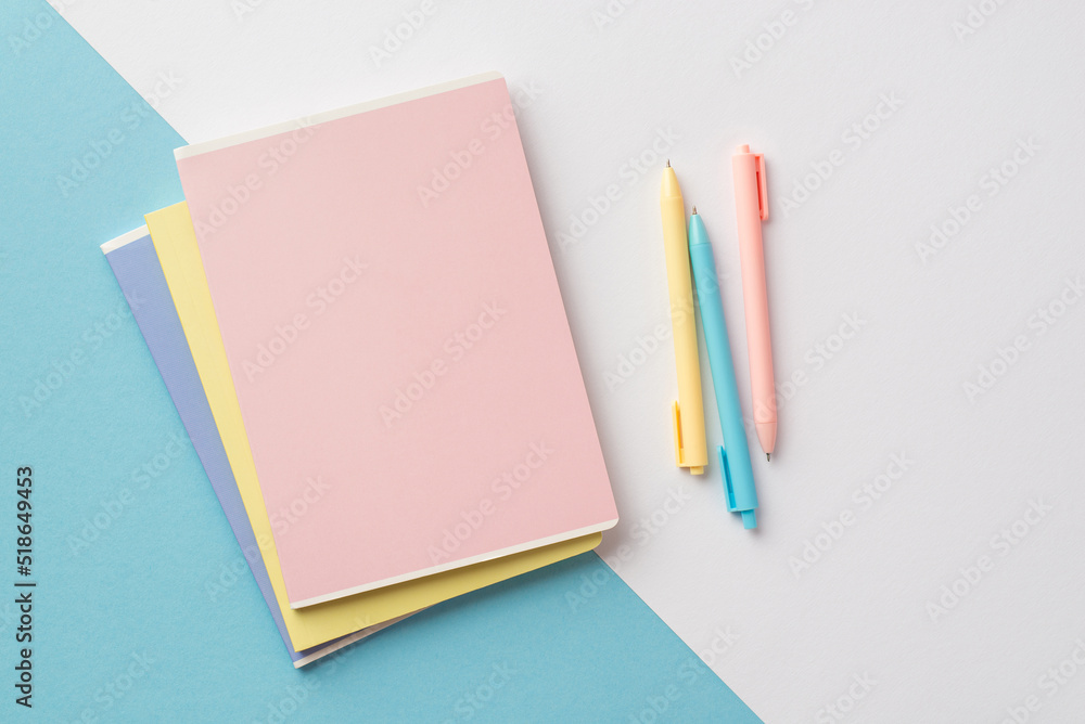 Back to school concept. Top view photo of colorful diaries and pens on bicolor blue and white background Back to school concept. Top view photo of colorful diaries and pens on bicolor blue and white background