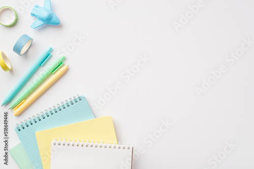 School accessories concept. Top view photo of colorful stationery diaries plane shaped sharpener pens and adhesive tape on isolated white background with empty space