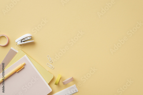Back to school concept. Top view photo of stationery diaries pen ruler clips mini stapler and adhesive tape on isolated pastel yellow background with copyspace photo