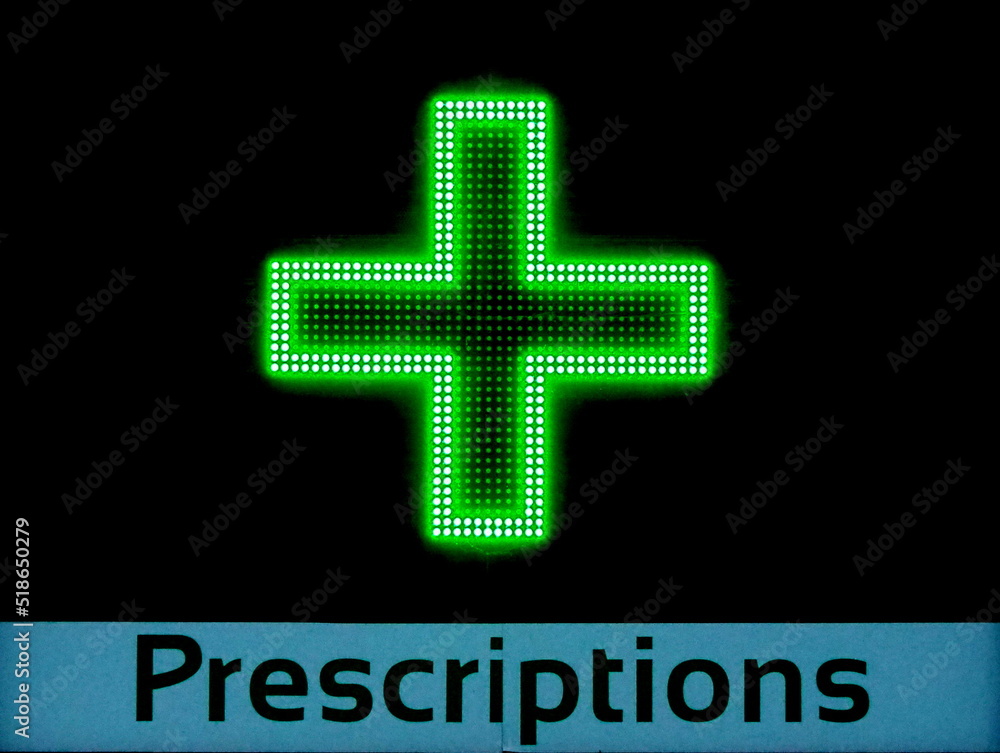 Fototapeta premium Pharmacy prescriptions with green neon cross on chemist shop building