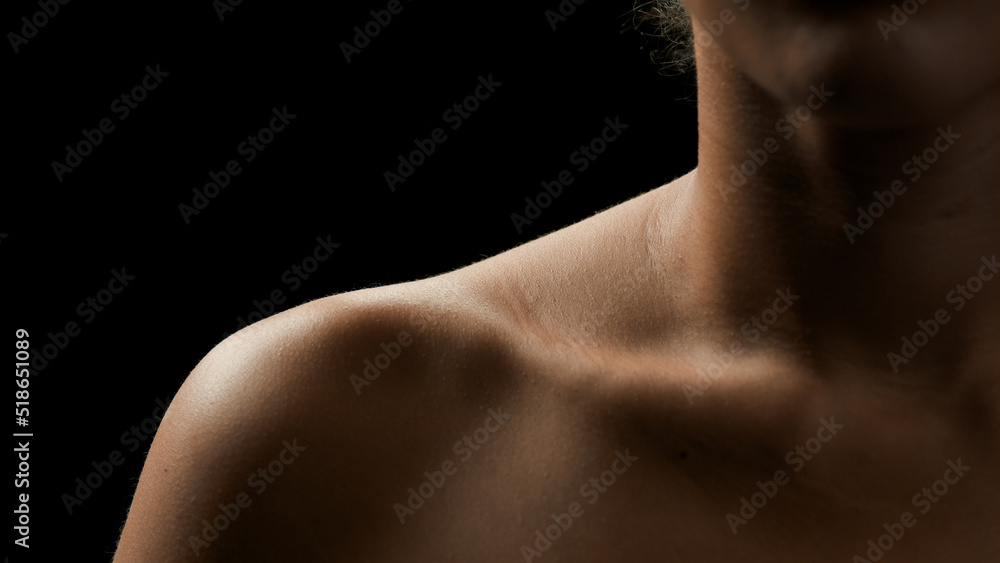 Big close-up shot of fit African American female model's clavicle on black background | Body care concept