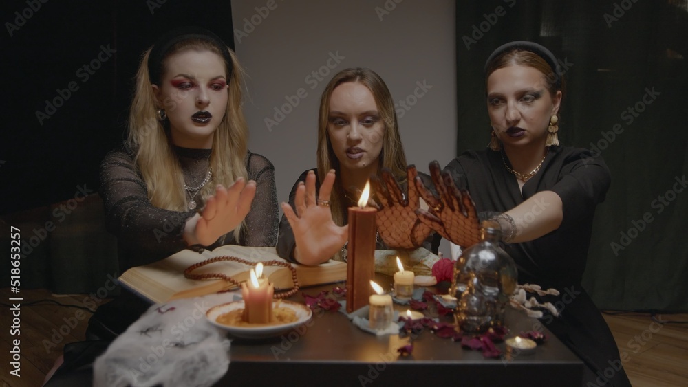 4K. Three female witches in a dark room conduct mystical sessions