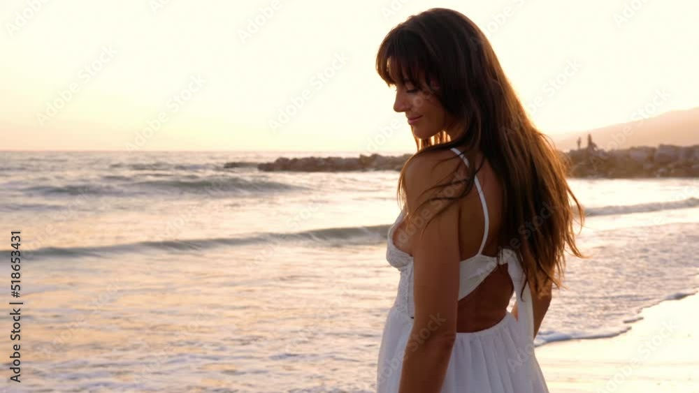 Beautiful woman in a white dress at the beach at sunset Beautiful woman in a white dress at the beach at sunset