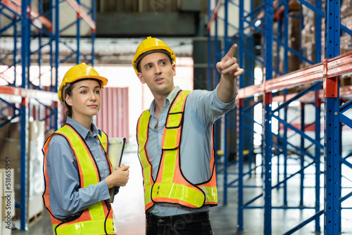 Engineer wearing safety vest controlling machine working talking with assistant engineer worker checking safety first for labour workers. Safety officer check box in warehouse.