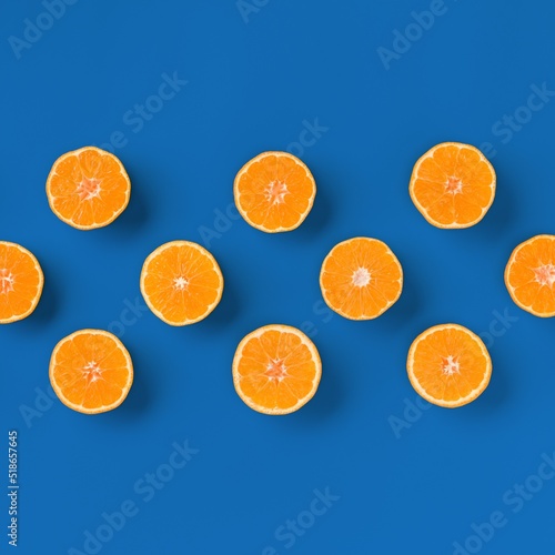 Fruit pattern of fresh orange tangerine or mandarin over blue background. Flat lay, top view. Pop art design, creative summer concept. Citrus in minimal style..