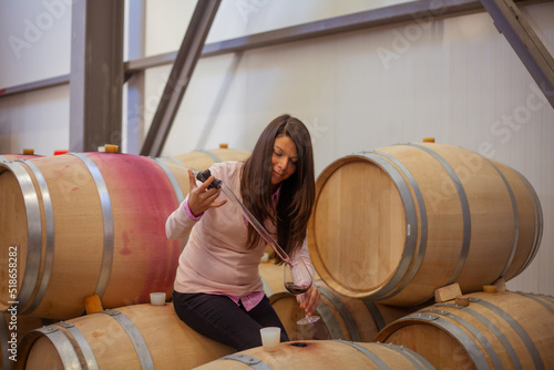 woman making a sample of red wine from barrel with a special tool