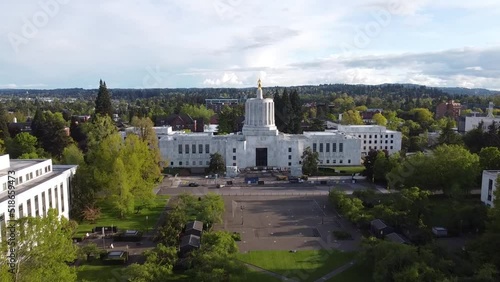 Aerial drone footage of the white building of the Oregon State Capitol with a green park in Salem photo