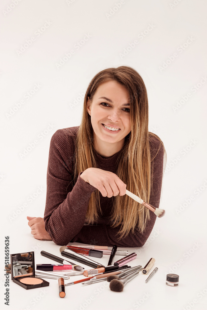 Beautiful woman makeup artist lies on a white background with makeup brushes