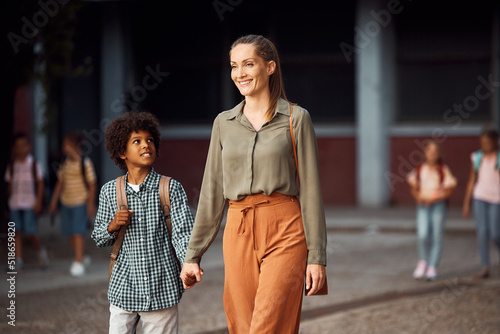 Happy mother and son holding hands while going to school.